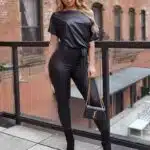 Femme en combinaison moulante en simili cuir noire sur un balcon.