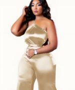Femme brune portant une combinaison en soie grande taille beige sur fond blanc.
