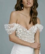 Femme portant une combinaison de mariage en dentelle blanche avec une longue traîne.