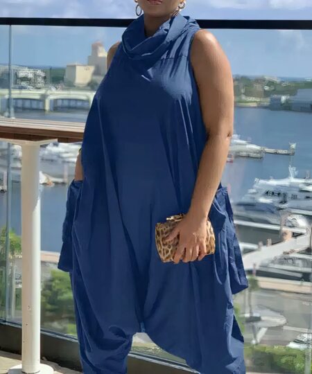 Femme brune portant une combinaison rétro sans manches grande taille bleue sur un balcon devant un port.