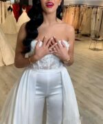 Femme portant une combinaison avec une longue traîne et un pantalon évasé dans une boutique de mariage.