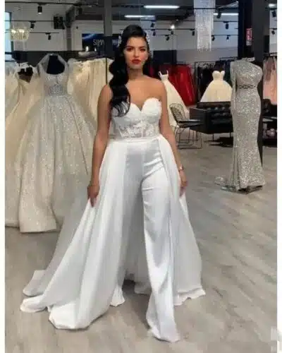 Femme portant une combinaison avec une longue traîne et un pantalon évasé dans une boutique de mariage.