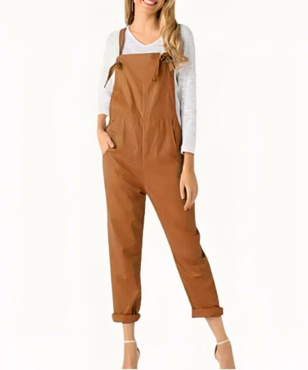 On voit une femme qui porte une combinaison salopette camel avec un tee-shirt manche longue blanc. Elle est blond aux cheveux longs.