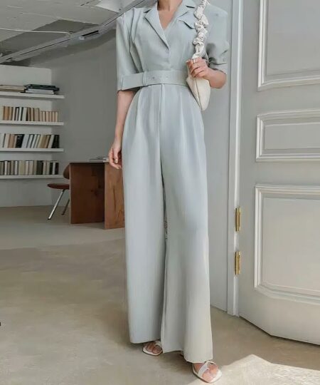 On voit une femme dans un appartement cossu qui porte une élégante combinaison bleue façon smoking. Elle a l'air d'être avocate, notaire ou juriste. Elle exerce un poste important.