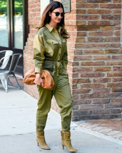 On voit une femme brune qui marche dans la rue. Elle porte une combinaison d'inspiration militaire, kaki.