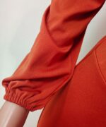 Détail de la manche d'une combinaison orange sur un mannequin en plastique.