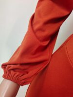 Détail de la manche d'une combinaison orange sur un mannequin en plastique.
