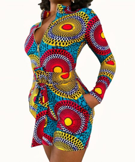 Combinaison short multicolore aux motifs ronds ethniques portée par une femme noire aux cheveux afro avec la main dans la poche.
