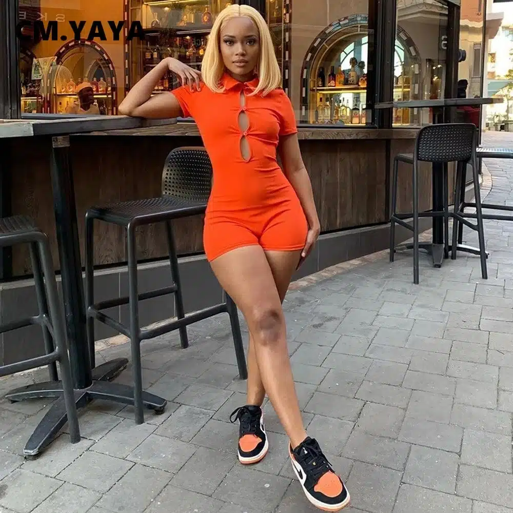 Femme portant une combinaison short orange côtelé dans la rue devant un restaurant.