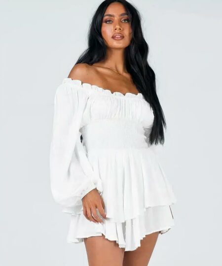 femme noire porte une combishort sexy chic blanche avec poches pour femme en regardant en face devant un fond uni