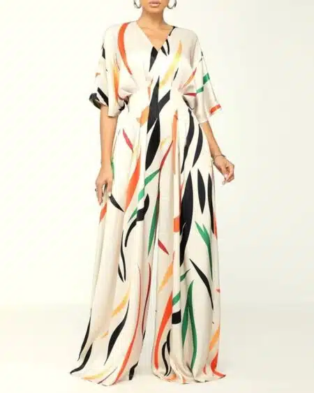 femme portant une combinaison chic imprimée à motifs abstraits en ayant les bras le long du corps sur un fond blanc.