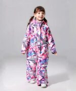 Combinaison de ski enfant une pièce avec capuche et imperméable portée par une petite fille sur fond gris