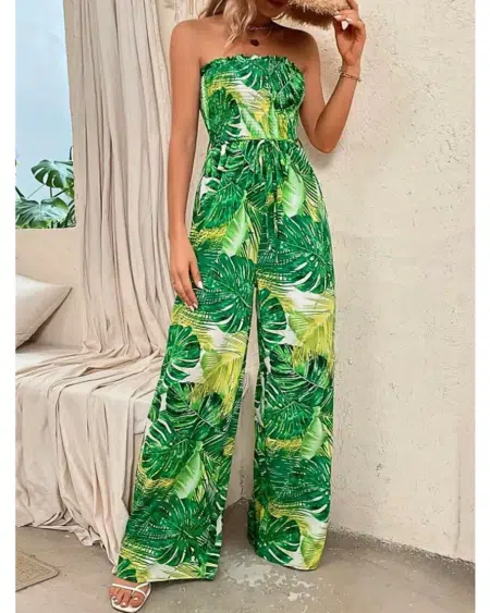 on voit une femme debout dans un salon clair, elle porte une combinaison à imprimé florale verte